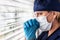 Stressed Female Doctor or Nurse Praying At Window Wearing Medical Face Mask