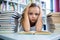 Stressed girl with books at table in school library