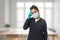 Stressed indian girl in wearing surgical mask and gloves looking at the camera, indoor exhausted sad woman, migraine headache pain