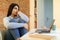 Stressed indian teen lady feeling demotivated while sitting at desk in front of laptop and studying remotely from home