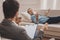 Stressed man lying on beige sofa explaining his problems to therapist