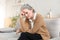 Stressed middle aged woman sit on sofa in living room, lost in thought