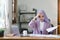 Stressed Muslim millennial businesswoman wearing a purple hijab working from home on laptop looking worried, tired and