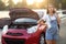 Stressed pregnant woman talking on phone near broken car outdoors