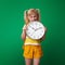 Stressed pupil with backpack biting clock on green background