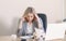 stressed puzzled blond businesswoman looking at diary, sitting in office, exhausted upset employee , having problem