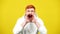 Stressed redhead man screaming out loud looking at camera. Portrait of handsome Caucasian millennial shouting at yellow