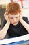 Stressed Schoolboy Studying In Classroom