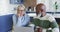 Stressed senior diverse couple in kitchen sitting at table, using laptop