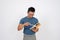 A stressed, serious Asian man is reading a book while standing on an isolated white background