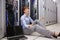 Stressed technician sitting on floor beside open server