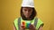 Stressed troubled young woman in hard hat and green vest playing fidget toy in slow motion and looking at camera