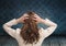 Stressed woman holding head by blue wall