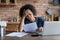 Stressed young african american woman looking at paper bills.