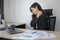 Stressed young business woman working on laptop with documents in modern office, workload concept