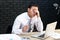 Stressed young businessman at table on dark background