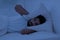 Stressed young indian man covering head with pillow while lying in bed