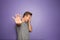 Stressed young man showing Stop gesture on color background