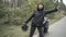 Stressed young woman hitchhiking on empty road with broken motorcycle standing at the background. Sad Caucasian biker