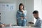 Stressed young woman standing near flipchart, feeling nervous.