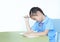 Stressful Asian little schoolgirl studying and tired with doing her homework on desk over white background. Kid girl use pencil