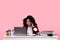 Stressful deadline. Scared woman looking at laptop at white desk on pink background