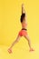 Stretch. Sport woman stretching body, legs on yellow background