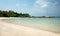 Stretched out white sand beach with natural rock formation at the coastline on the horizon in Belitung Island.