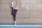 Stretching gymnast woman doing vertical split, twine in brown urban wall background