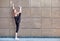 Stretching gymnast woman doing vertical split, twine in brown urban wall background