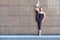 Stretching gymnast woman doing vertical split, twine in brown urban wall background