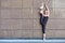 Stretching gymnast woman doing vertical split, twine in brown urban wall background