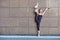 Stretching gymnast woman doing vertical split, twine in brown urban wall background