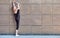 Stretching gymnast woman doing vertical split, twine in brown urban wall background