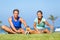 Stretching happy runners group doing leg stretch together on run class outside in summer grass doing jogging warm-up