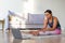 Stretching at home online. African American woman exercising at home in front of a laptop monitor.