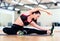 Stretching young woman with earphones in the gym