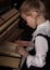 Strict little girl in a big glasses playing the piano, child imitates teacher