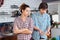 Strict unhappy woman cooking with her husband on kitchen