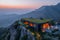 A striking, contemporary house with a green roof, perched on a mountain peak. The first light of day highlights the Easter-themed