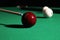 Striking red billiard ball with cue