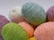 String decorated colored Easter eggs piled up close on a white background