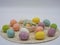 String decorated Easter eggs on a round cream placemat with a white bowl of candies in the center.  Pastel colors perfect for