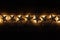 A string of golden star christams lights on a dark wooden background