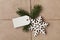 String or twine tied in a bow with tag, fir tree and wooden snowflake on kraft paper
