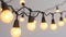 String of warm glowing light bulbs against a soft gray background, giving a cozy ambiance