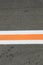 Strip of white and orange colors on a gray asphalt