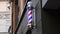 Striped barber pole rotating on wall of hairdresser shop in old building