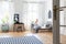 Striped carpet and windows in white teenager`s room with black chair at desk near bed