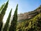 A striped cliff in Montserrat mountains and three cone-shaped fir-trees in the foreground